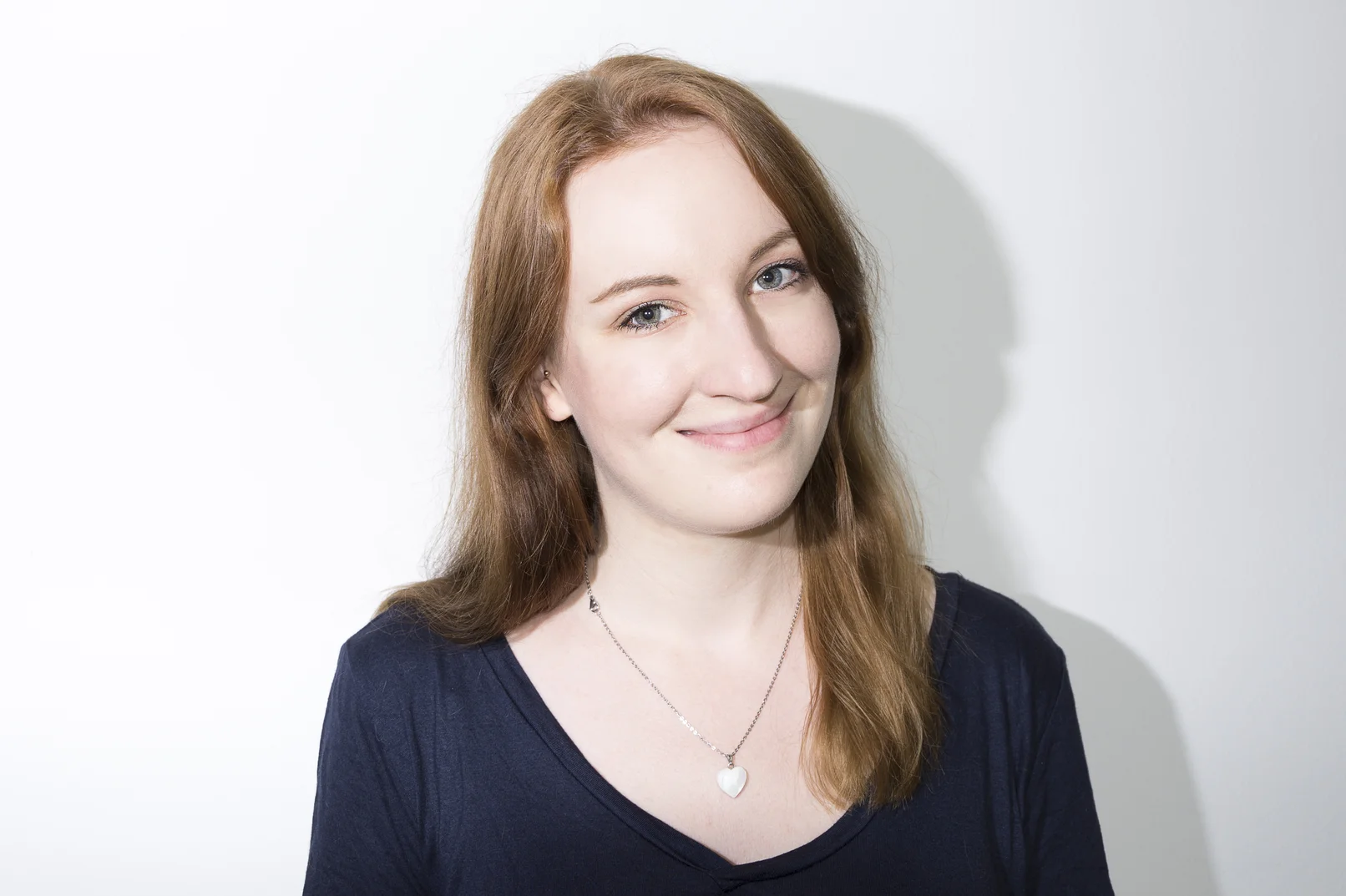Frau vor weißem Hintergrund, die freundlich in die Kamera guckt
