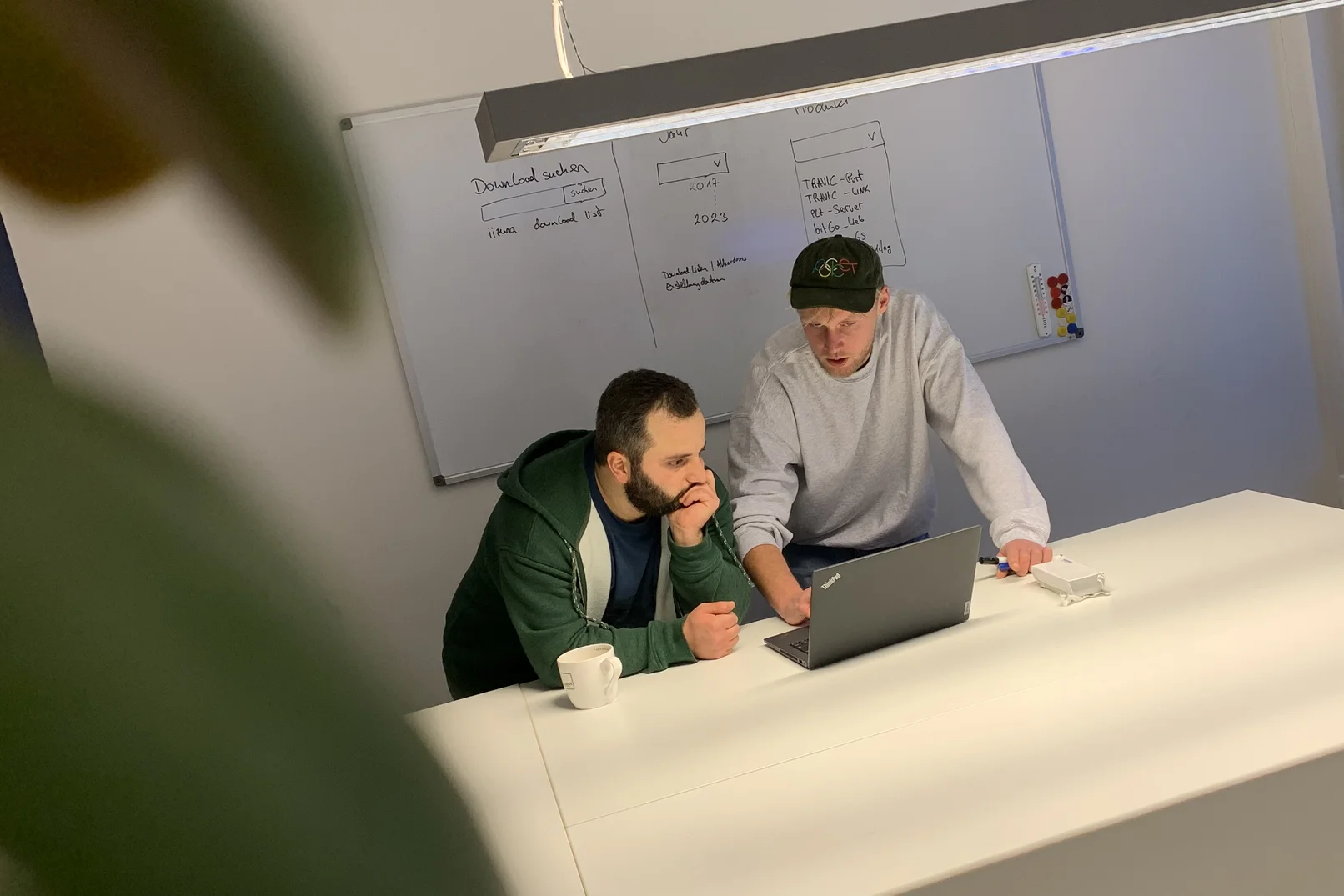 Zwei Männer schauen gemeinsam auf einen Laptop und diskutieren