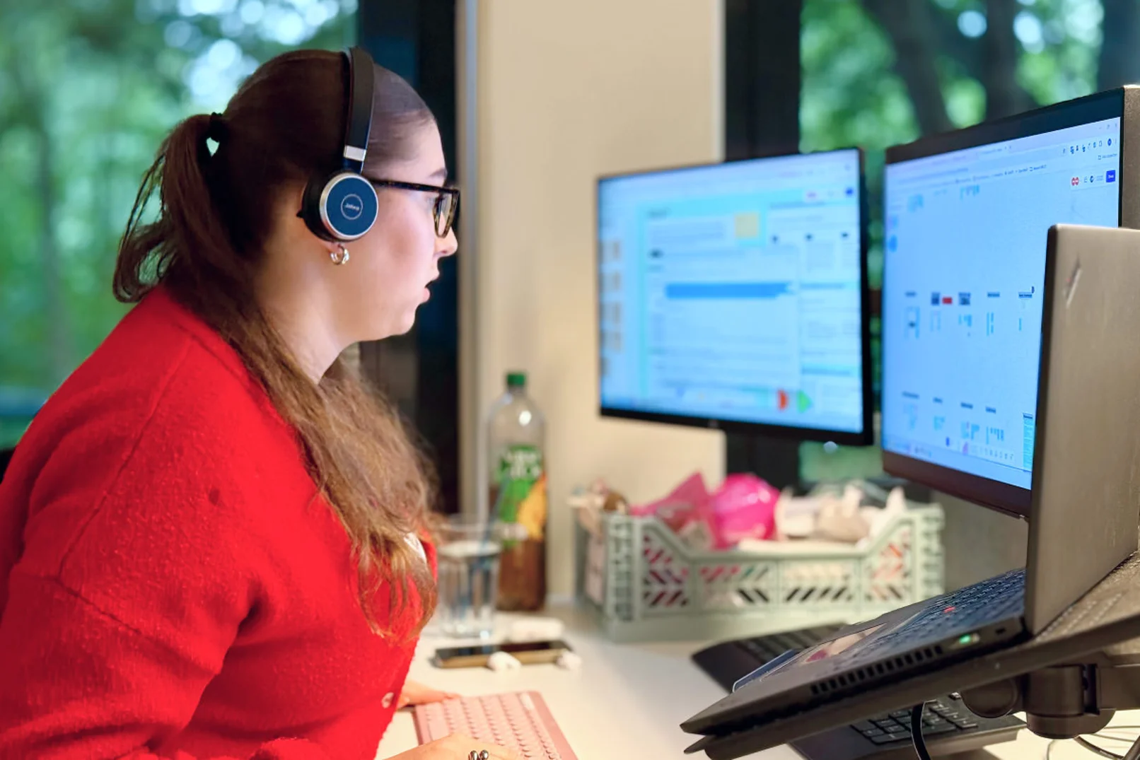 Person mit Headset schaut auf drei Bildschirme