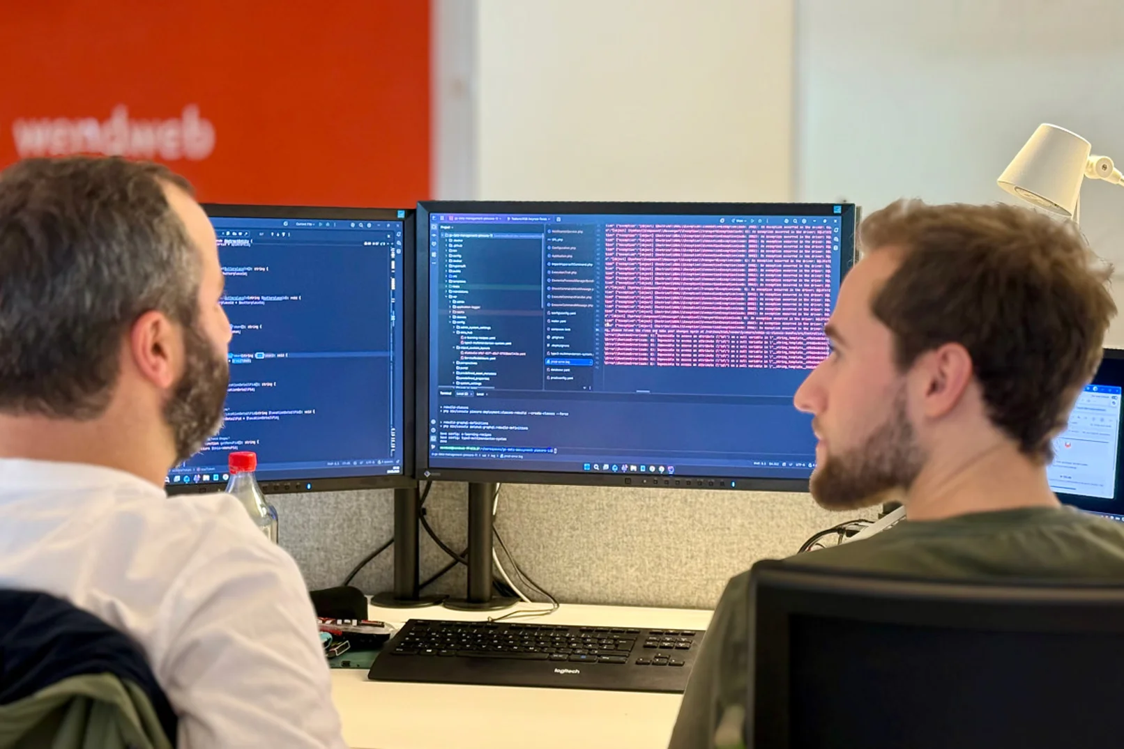 Abstimmung von zwei Entwicklern vor einem Bildschirm mit Code