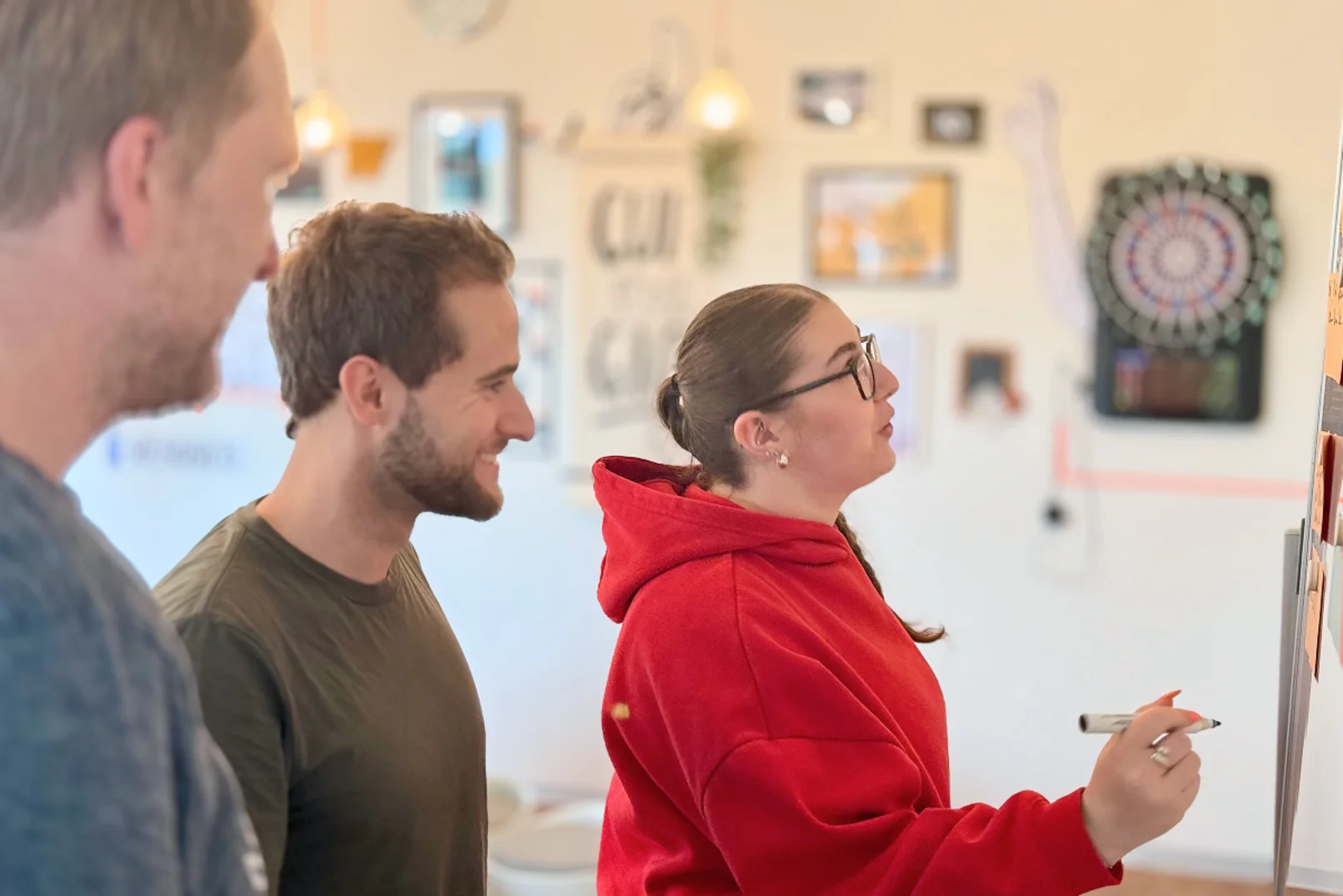 Drei Personen schauen gemeinsam auf ein Whiteboard