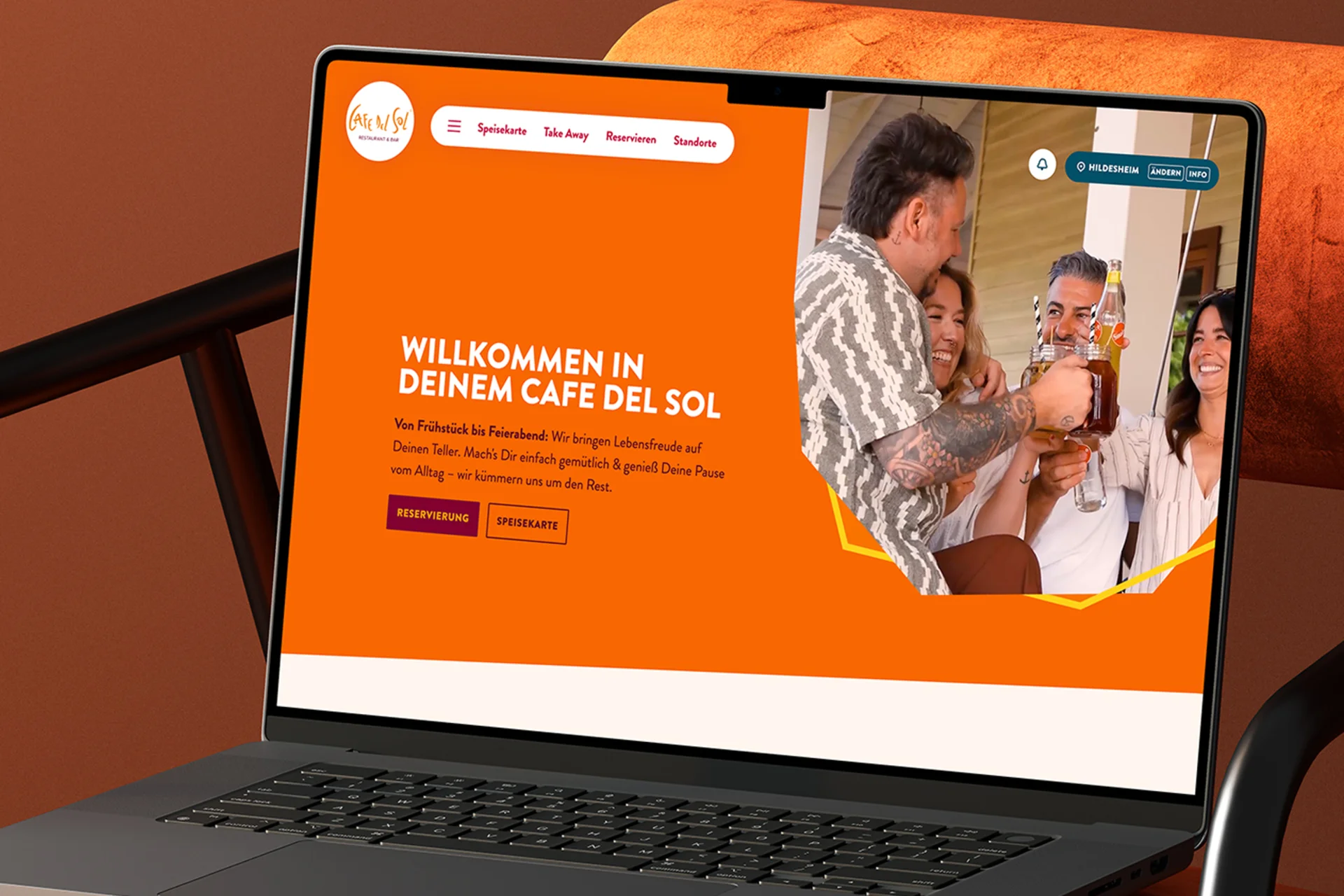 Laptop auf einem orangefarbenen Stuhl mit geöffneter Cafe del Sol Website