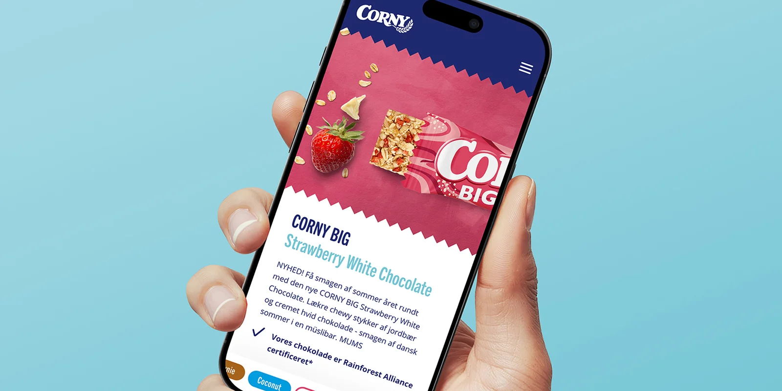Hand hält Smartphone mit geöffneter Corny Website mit Produktabbildung eines Müsliriegels 