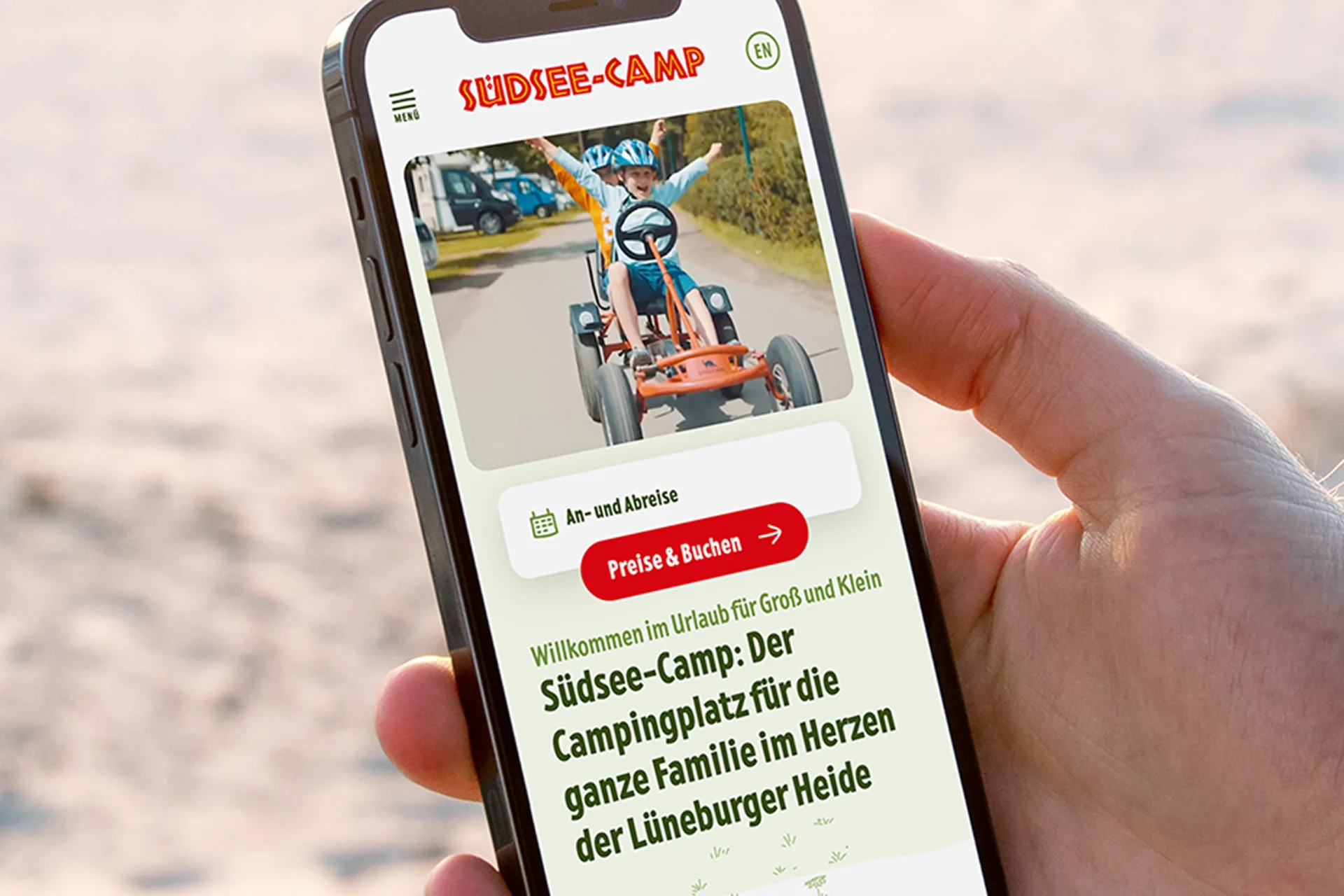 Eine Hand hält ein Smartphone, auf dem die Website des Südseecamps geöffnet ist